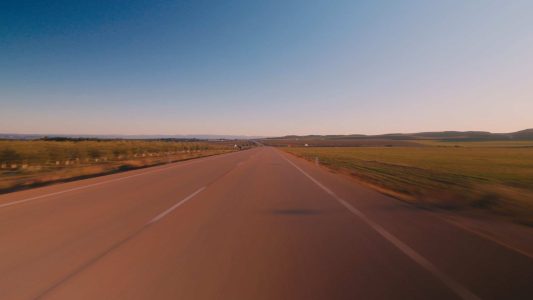 Camino rural en Huesca al atardecer, rodeado de campos abiertos y cielo despejado.