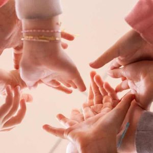 Manos de niños y adultos entrelazadas en un acto de unión y colaboración.