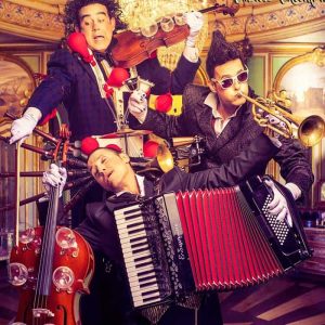 Banda de músicos en Festival Imaginaria tocando instrumentos en un escenario colorido.