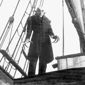 Escena de un personaje misterioso en un escenario teatral.